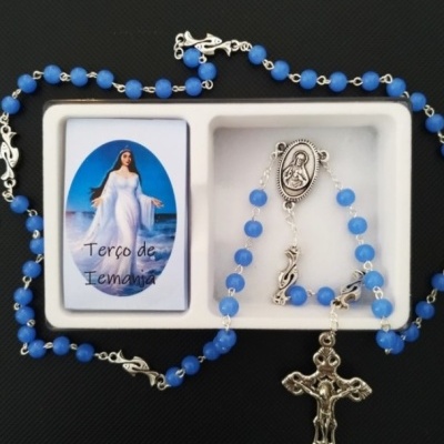 Terço com contas azuis, crucifixo prateado e cartão 'Terço de Iemanjá' numa caixa branca