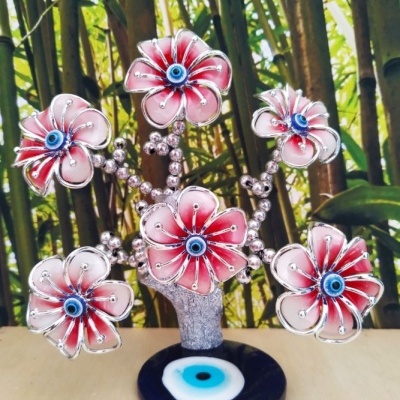 Árvore decorativa com flores rosa e centro azul em base preta com círculo azul