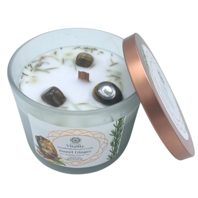 Vela aromática com pedras decorativas e tampa rosa ouro ao lado.