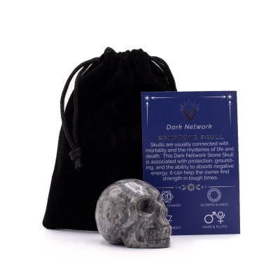 Caveira esculpida em pedra cinza e preto com saco de veludo e cartão explicativo azul