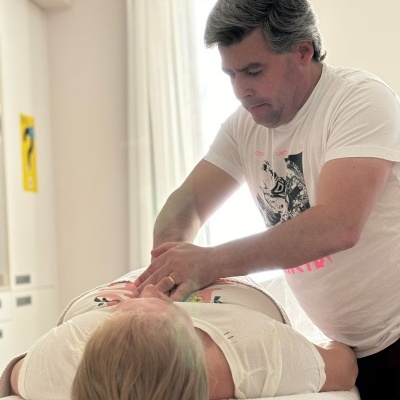 Homem a fazer massagem torácica a outro homem deitado numa cama branca.