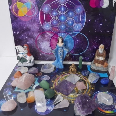 Cristais coloridos e estatuetas em tapete místico com fundo espacial roxo