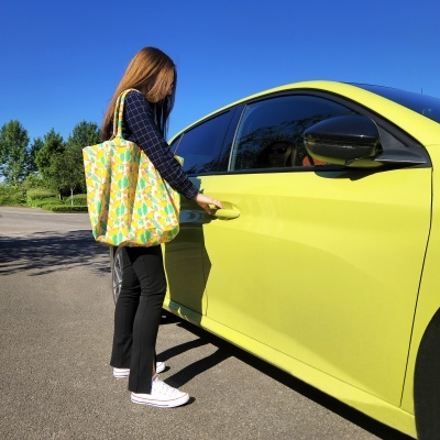 Pessoa a abrir porta de carro amarelo-limão com bolsa colorida tiracolo