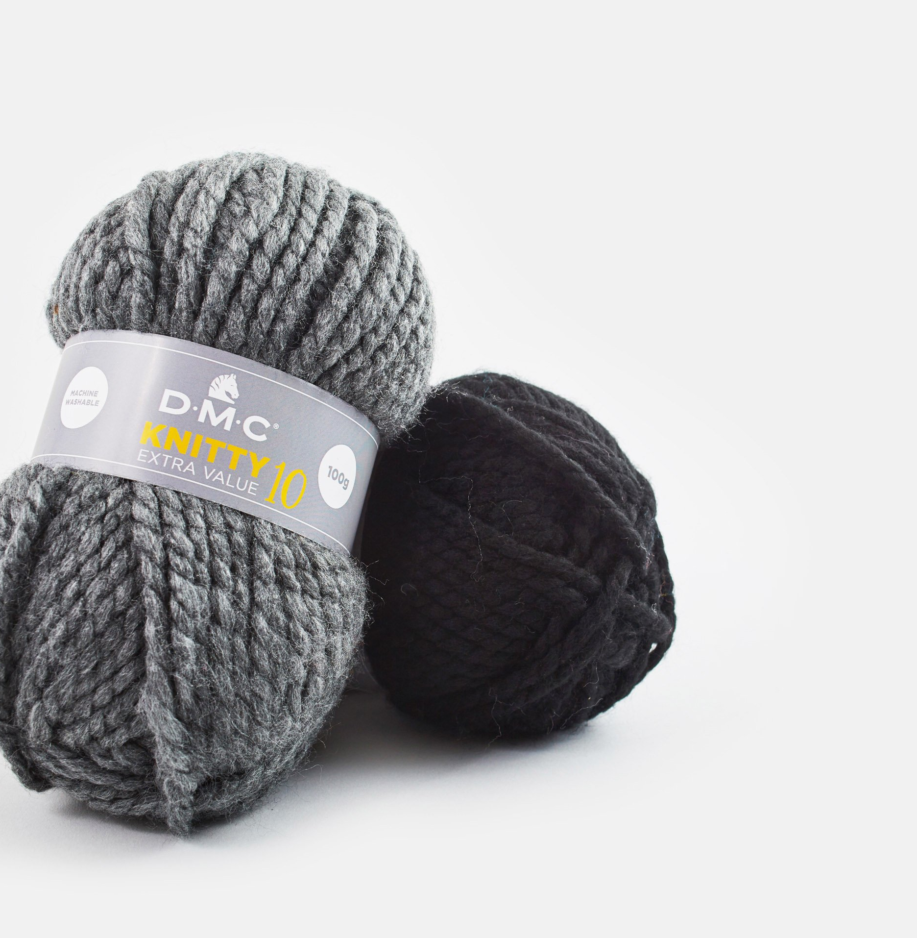 Dois novelos de lã, um cinza com etiqueta e outro preto, sobre fundo branco