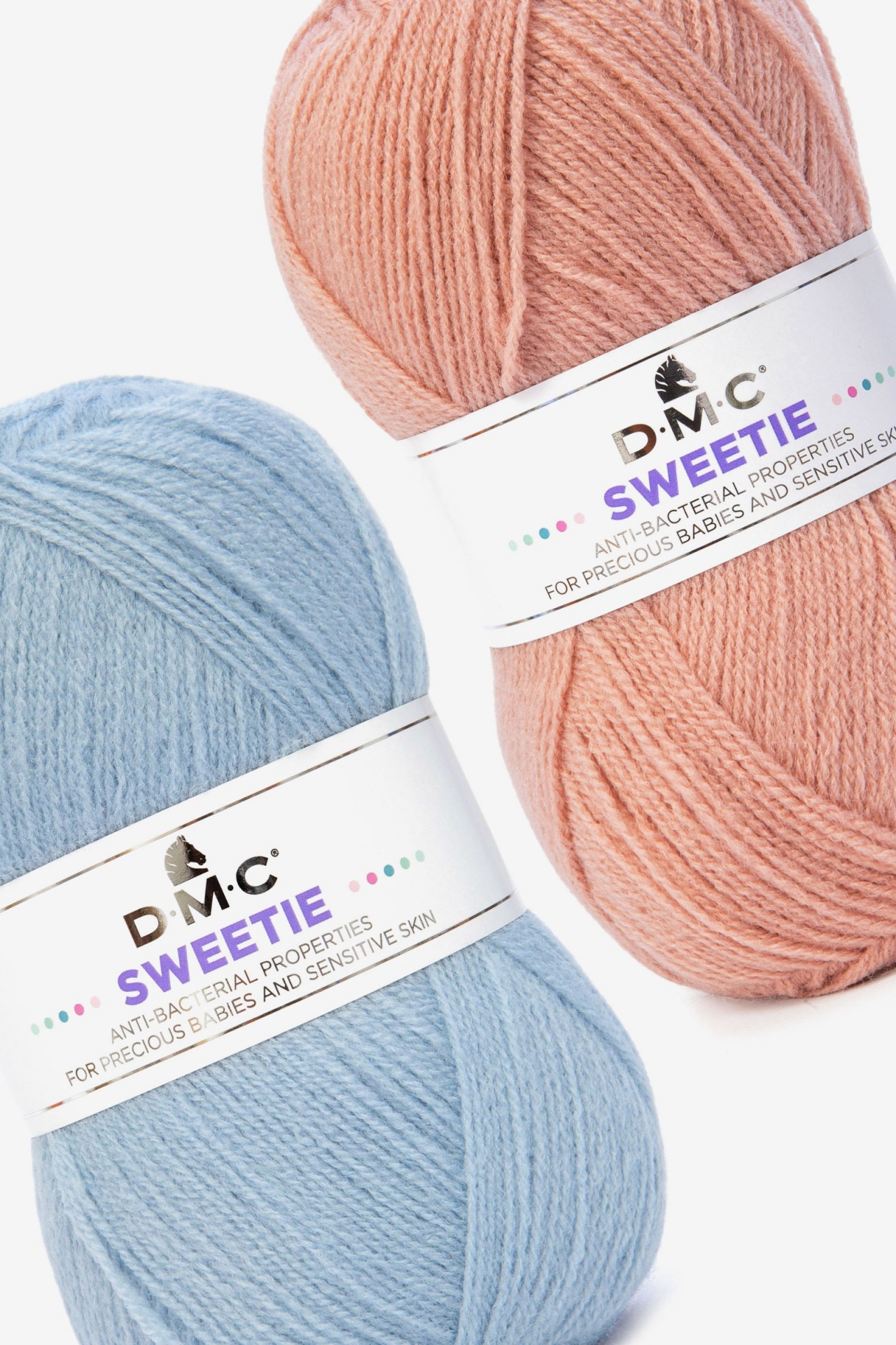 Dois novelos de lã D.M.C. azul claro e rosa com etiquetas 'SWEETIE' anti-bacterianas