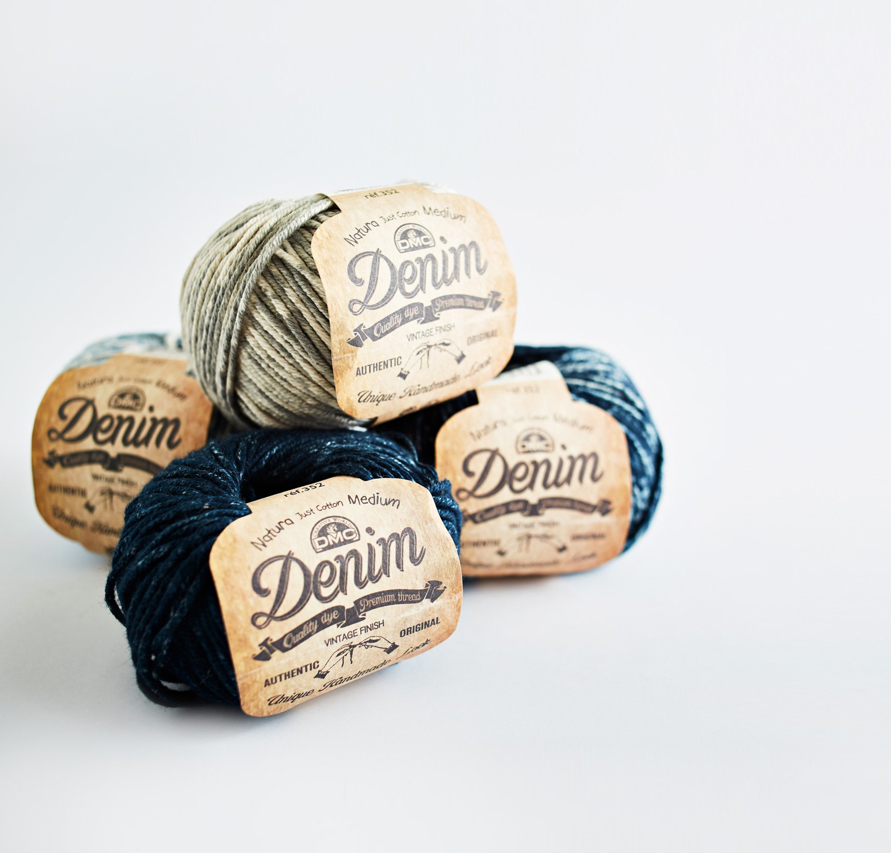 Quatro novelos de lã BMC Denim em azul, bege e castanho com etiquetas de papel reciclado