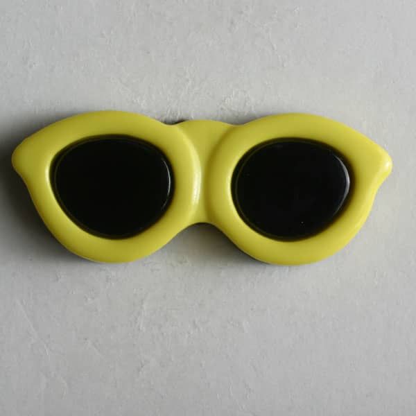 Óculos de sol amarelos com lentes pretas sobre superfície cinzenta.