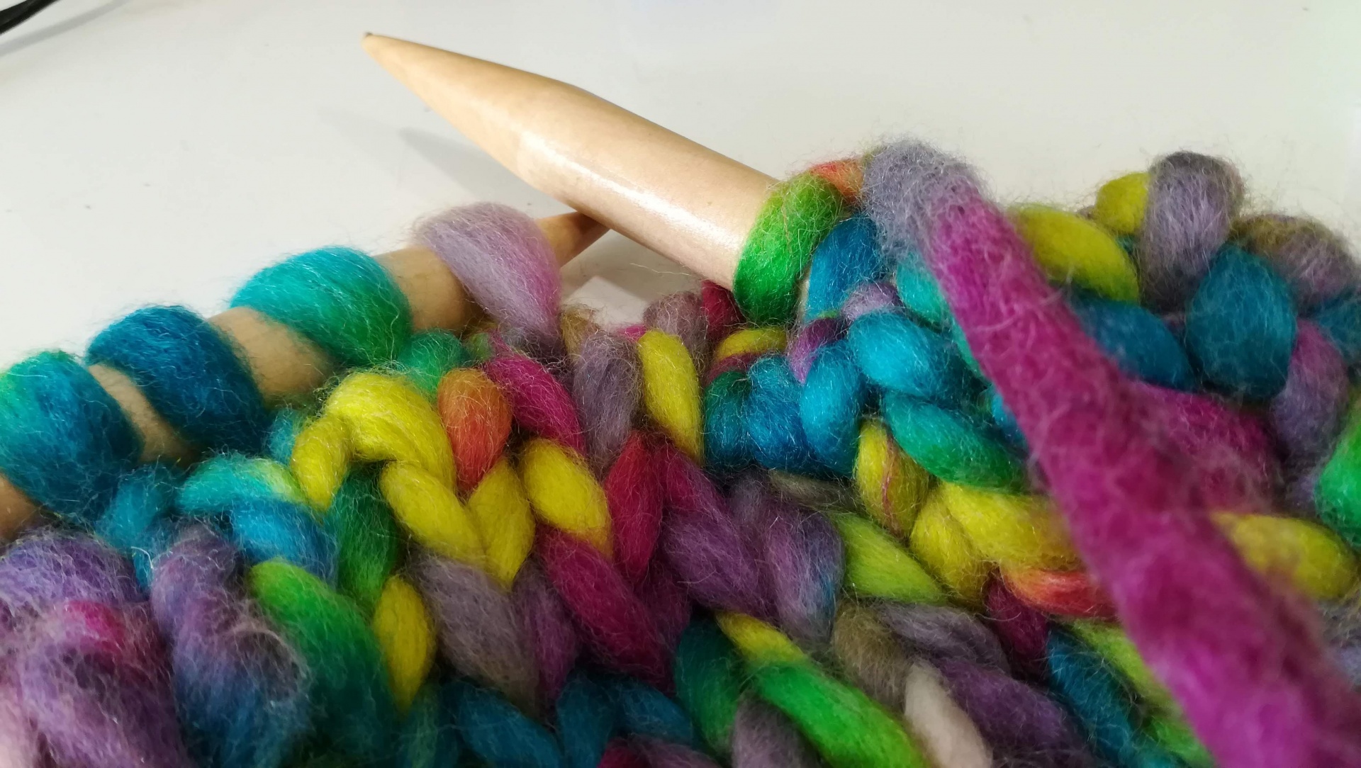 Novelo de lã colorida e agulha de tricô de madeira clara