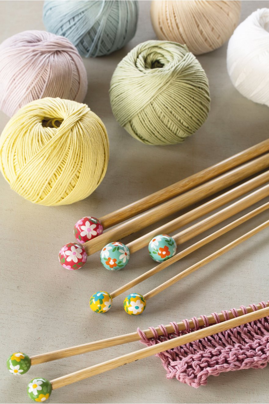 Agulhas de tricô de madeira com pontas florais e novelos de linha colorida pastel