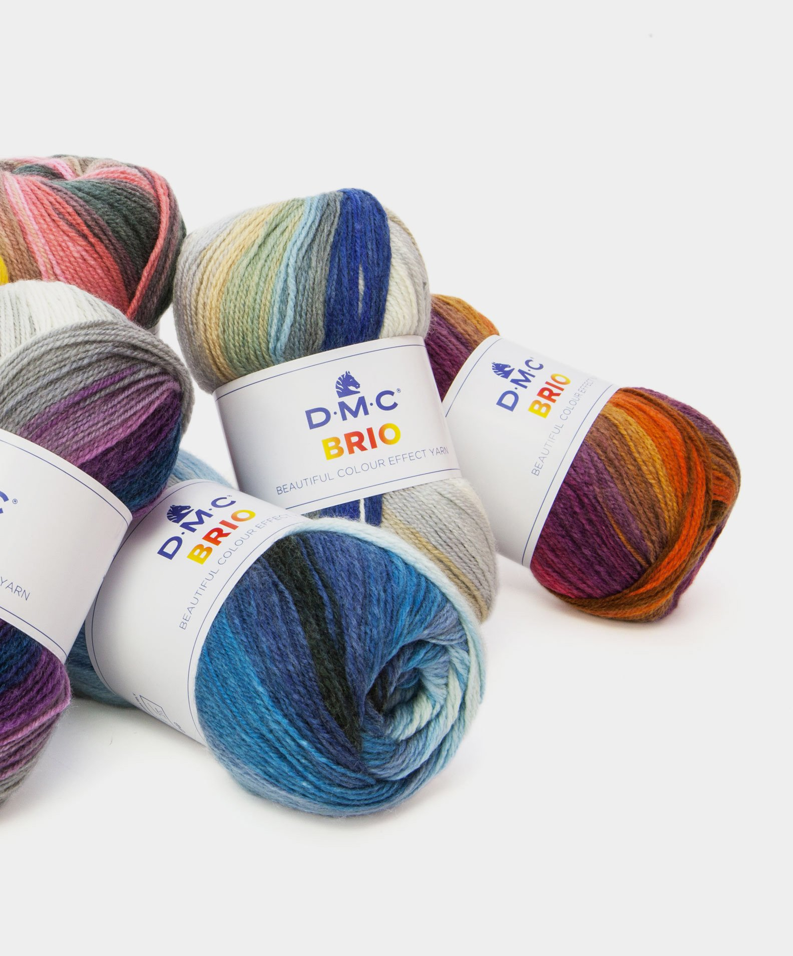 Quatro novelos de lã multicolorida DMC BRIO sobre fundo branco