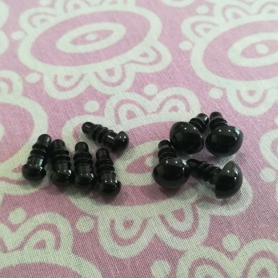 Olhos de segurança pretos redondos sobre tecido rosa com padrão floral branco