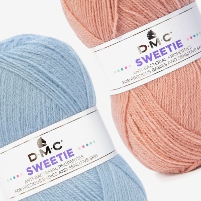 Dois novelos de lã D.M.C. azul claro e rosa com etiquetas 'SWEETIE' anti-bacterianas