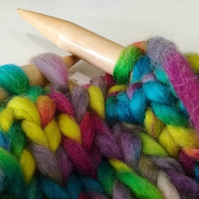 Novelo de lã colorida e agulha de tricô de madeira clara