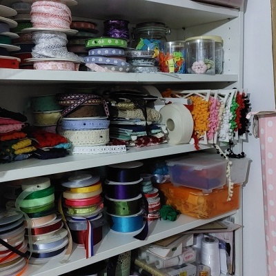 Prateleira com rolos de fitas coloridas e fios brancos e rosas