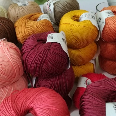 Novelos de lã coloridos com etiquetas em superfície clara