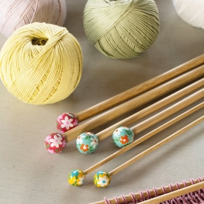Agulhas de tricô de madeira com pontas florais e novelos de linha colorida pastel