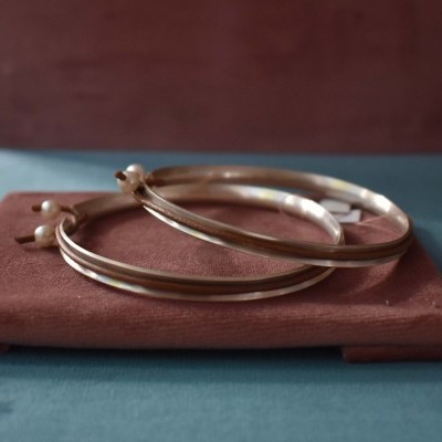 Brincos argola dourados sobre base de veludo castanha