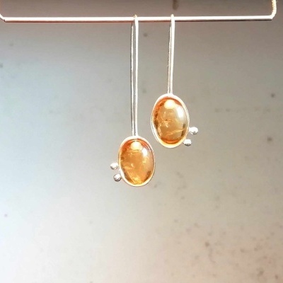 Brincos pendentes com pedras ovais douradas e estrutura metálica prateada