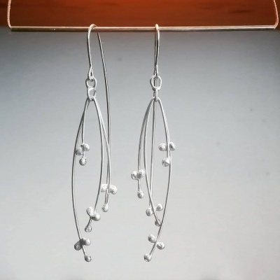 Brincos prateados em forma de ramos com esferas decorativas