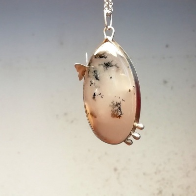 Colar com pendente oval translúcido com manchas pretas e moldura prateada