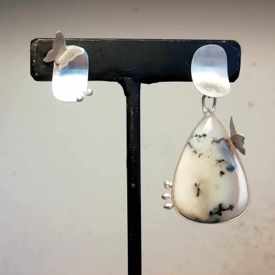 Brincos prateados com pedra branca e preta e borboletas em suporte preto