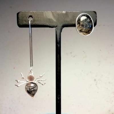 Brincos prateados com pedras escuras em suporte preto