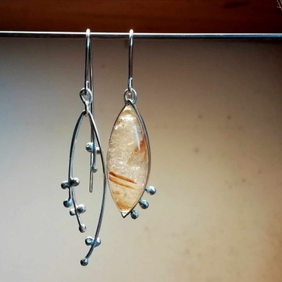 Brincos pendentes com pedra oval translúcida e estrutura metálica prateada