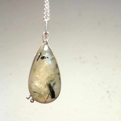 Pendente em gota de pedra translúcida com inclusões negras numa corrente prateada