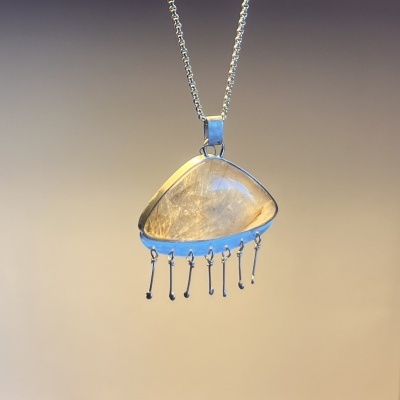 Colar com pendente triangular em pedra semi-transparente com inclusões douradas e detalhes metálicos pendurados