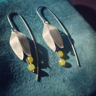 Brincos de metal prateado com folhas e esferas amarelas