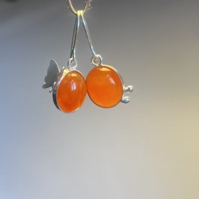 Brincos pendentes com pedras ovais laranja e detalhes em prata.