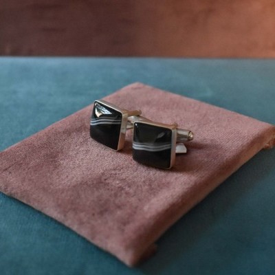 Botões de punho quadrados com pedras negras e padrões brancos sobre saco de tecido castanho