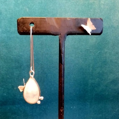 Brincos prata forma de gota pendurados em suporte preto com borboleta