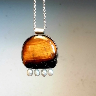 Colar com pendente olho de tigre e pérolas suspenso numa corrente prateada