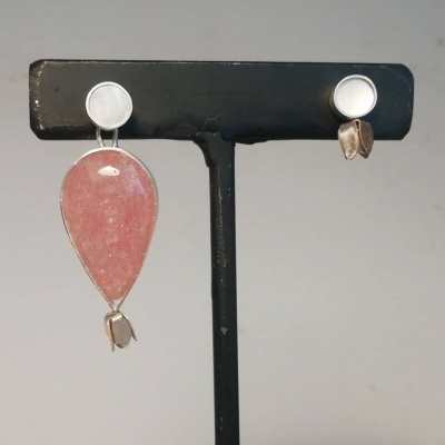 Brincos rosa e prateados num suporte preto