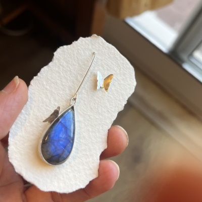 Brincos com pedra azul em lágrima e borboletas metálicas em cartão branco texturizado
