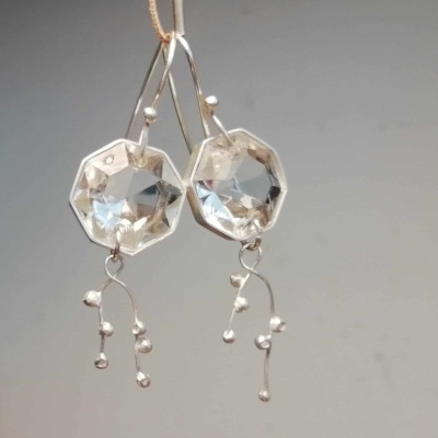 Brincos prateados com pedras facetadas octogonais e detalhes pendentes