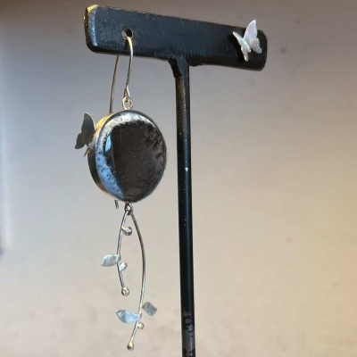 Brinco com pedra oval preta e detalhes metálicos prateados