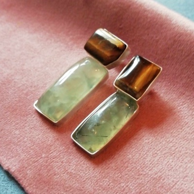 Brincos com pedras verdes e castanhas sobre tecido rosa