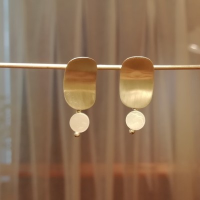 Brincos dourados ovais com pendente branco em suporte metálico