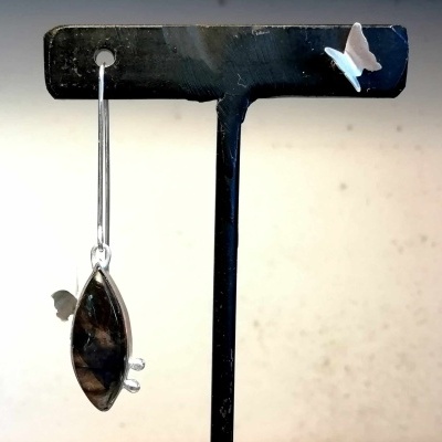 Brinco pendurado em suporte preto com pedra escura e borboleta no suporte