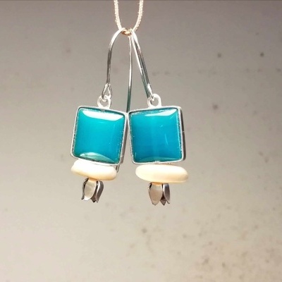 Brincos azuis quadrados com contas brancas em fundo neutro