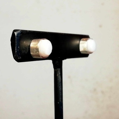 Botões de punho metálicos com superfície branca em suporte preto