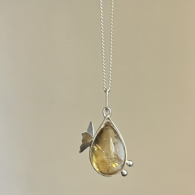 Colar com pendente de gota em pedra amarela e detalhe de borboleta