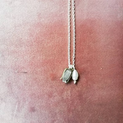 Colar metálico prateado com pendentes em fundo rosa