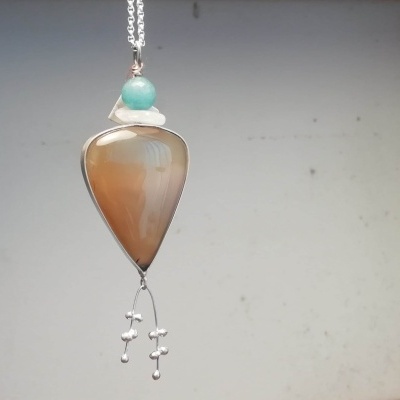 colar com pendente em forma de gota castanho e detalhes em verde e branco com penduricalhos prateados