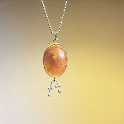 Colar com pendente oval laranja translúcido e enfeites metálicos prateados