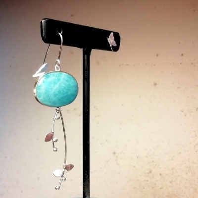 Brinco pendente com pedra azul turquesa e detalhes prateados em suporte preto