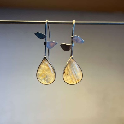 Brincos pendentes com pedras amarelas em forma de gota e detalhes de folhas prateadas