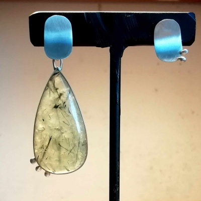 Brincos com base prateada e pendentes transparentes em forma de gota com inclusões negras